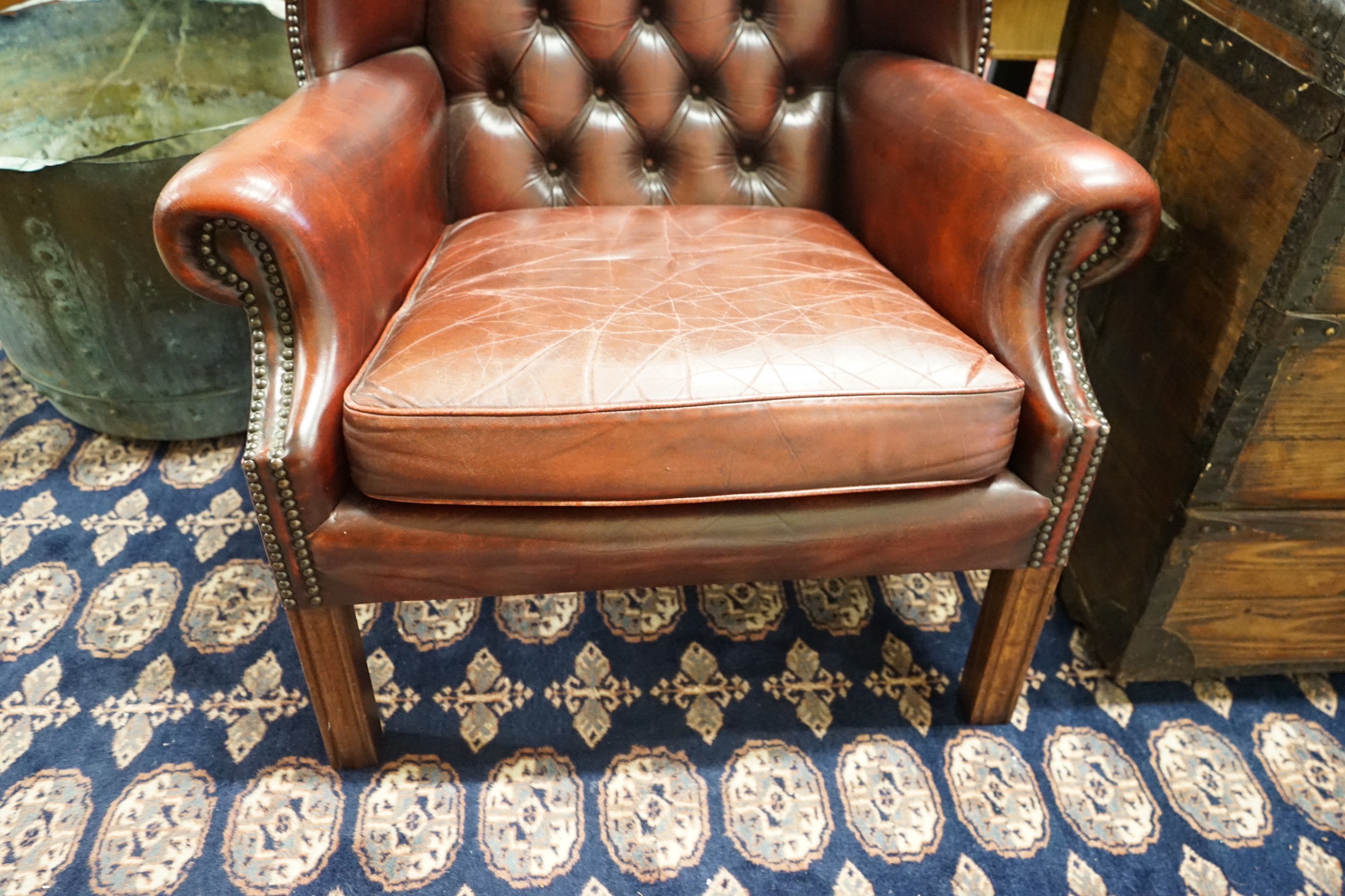 A George III style button back burgundy leather wing armchair, width 83cm, depth 66cm, height 82cm